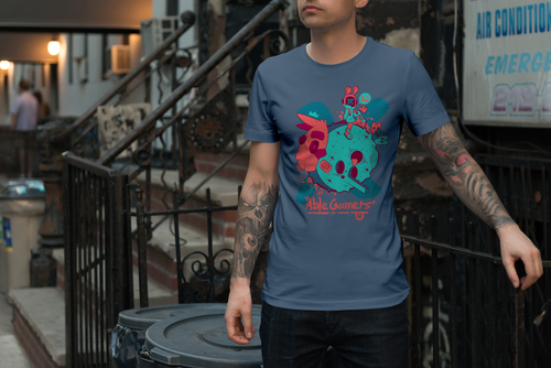 Guy on the streets wearing an indigo colored shirt (a blue grayZ) with a teal and watermelon colored moon with a face and a rabit man sitting on top of the moon. AbleGaemrs under the moon. 