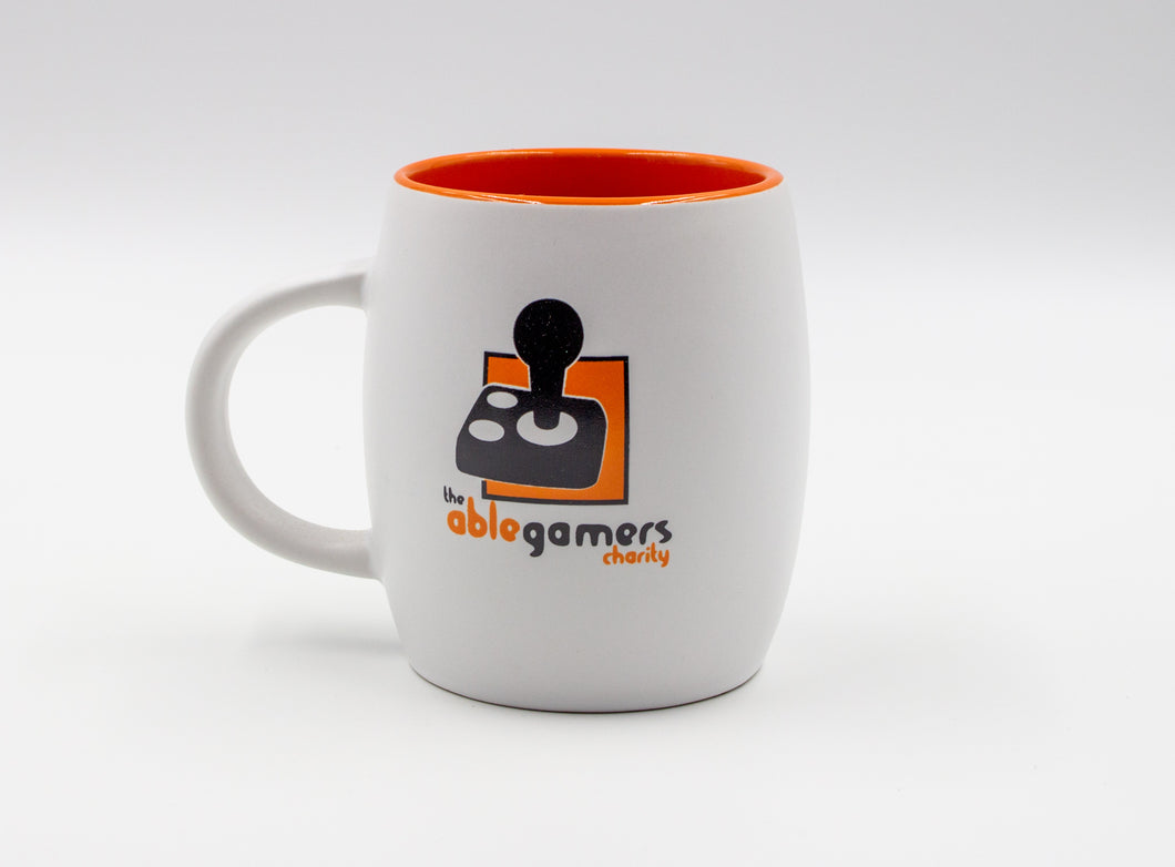 White Mug with the AbleGamers Logo (80s Joystick on orange square). The top of the mug going inside is shiny orange.